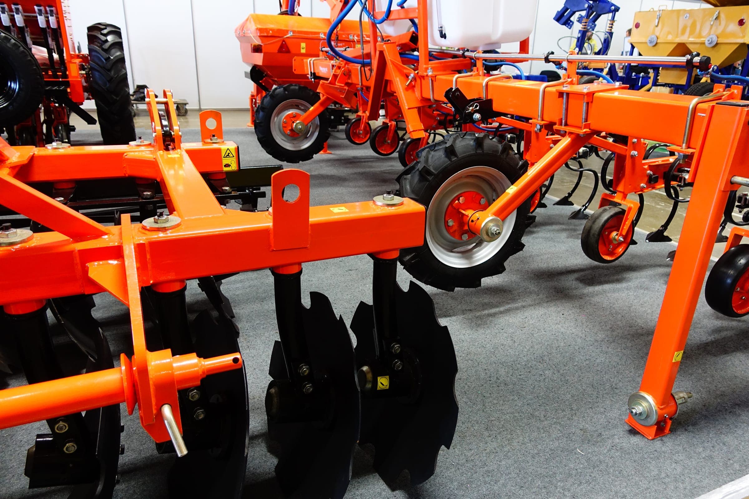 Orange cultivators and disc harrows in a showroom