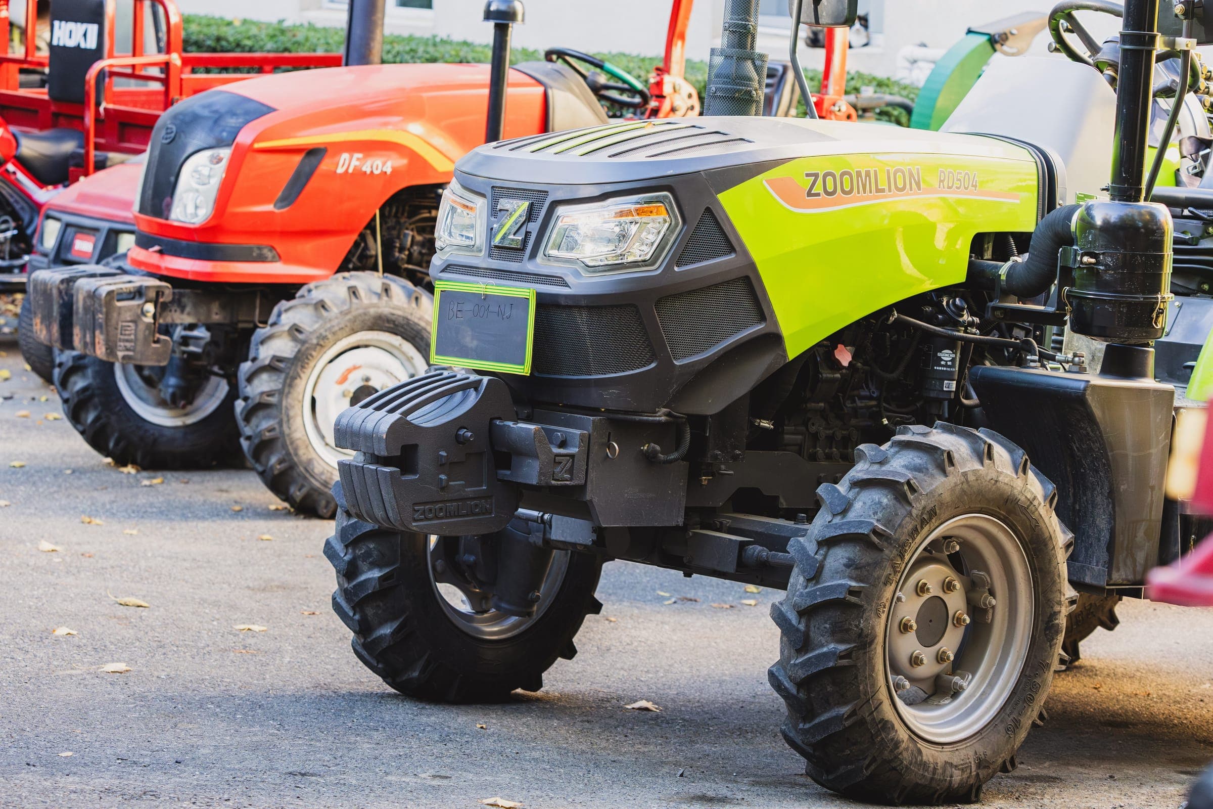Compact green and orange tractors on display
